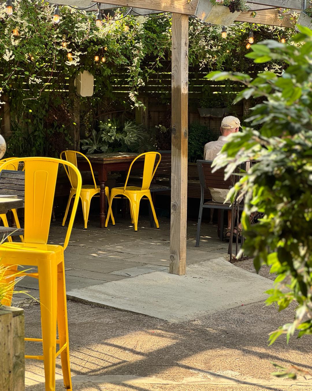 The leafy Delaval Arms garden with bright yellow chairs