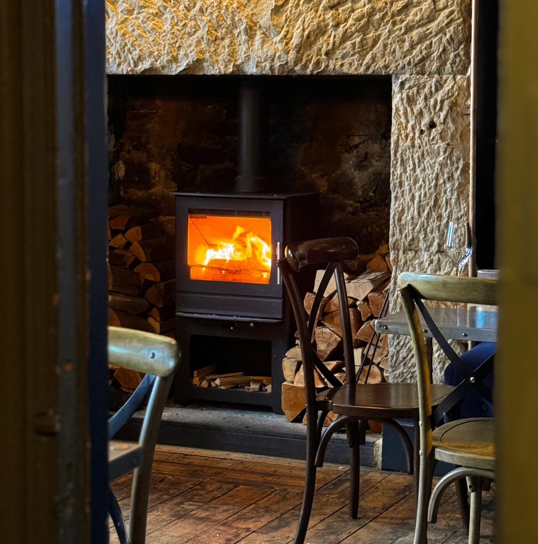 A glowing wood fire in the stone fireplace at the Delaval Arms